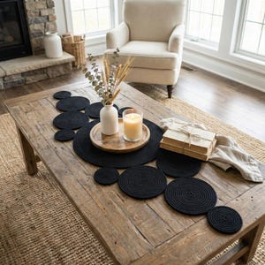 May include: Cozy and bright living room featuring a long handmade black cotton table runner draped beautifully across a rustic wooden coffee table. Styled with a decorative tray, warm pillar candles, and dried florals, complementing the comfortable beige armchairs.