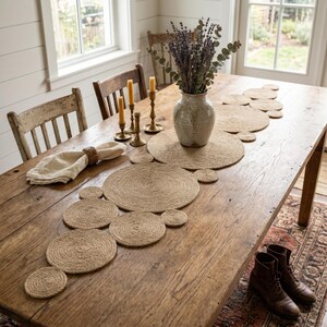 Country dining table with a jute disc runner, a stoneware jug of lavender, brass candlesticks and a linen napkin in a woven ring