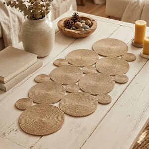 May include: A jute table runner and coasters set. The runner and coasters are made from tightly wound rope, creating a textured, circular design. The neutral colour palette complements the rustic aesthetic, ideal for a dining or coffee table setting.