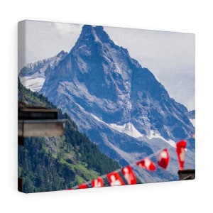 Op de afbeelding: Een schilderachtig uitzicht op een besneeuwde bergtop met een reeks rode Zwitserse vlaggen op de voorgrond.