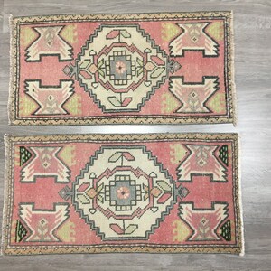 May include: Two pink and cream patterned rugs with intricate geometric designs. The rugs have a fringed edge and are made of a soft, woven material.