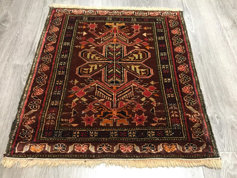 May include: A traditional Turkish rug with a dark red background and intricate geometric patterns in shades of red, orange, yellow, and green. The rug has a fringe border.