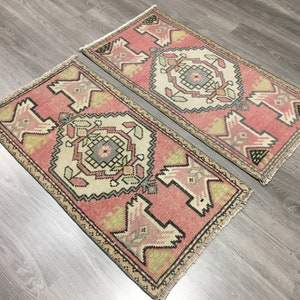 May include: Two pink and cream patterned runner rugs with fringed edges. The rugs have a traditional geometric design with black and green accents.