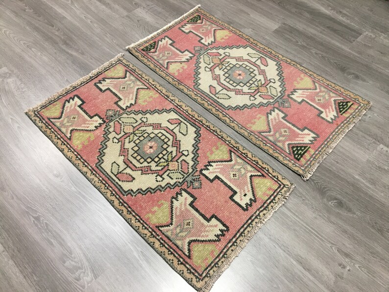 May include: Two pink and cream patterned runner rugs with fringed edges. The rugs have a traditional geometric design with black and green accents.