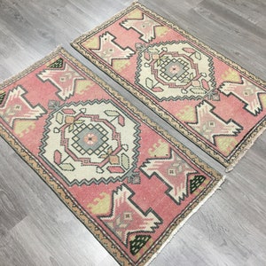 May include: Two pink and cream patterned rugs with a geometric design. The rugs have a fringed edge.