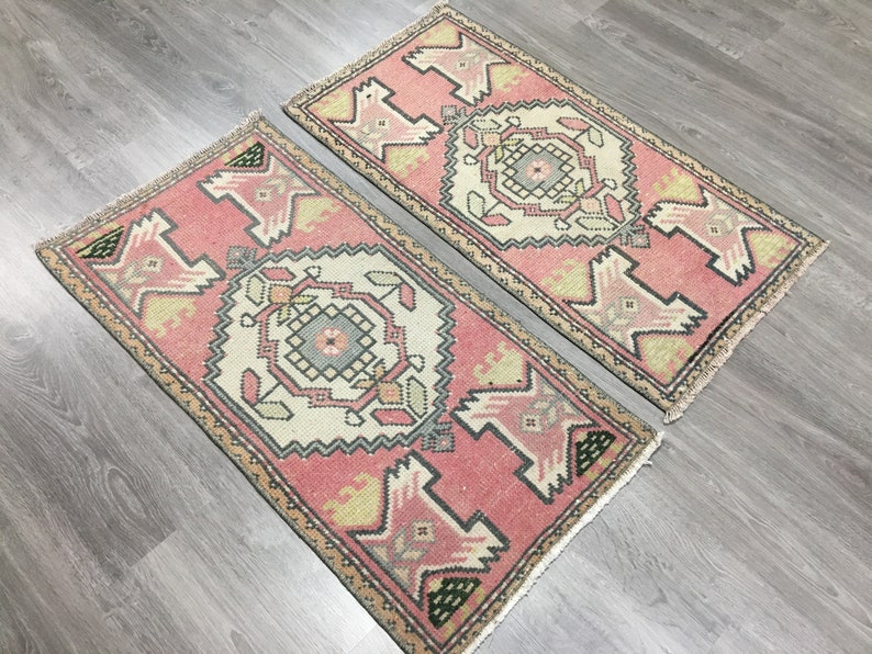 May include: Two pink and cream patterned rugs with a geometric design. The rugs have a fringed edge.