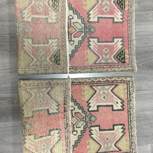 May include: Two pink and cream colored vintage Turkish kilim rugs with geometric patterns. The rugs are folded in half and have fringe on the ends.