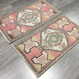 May include: Two pink and cream patterned runner rugs with geometric designs. The rugs have a fringed edge.