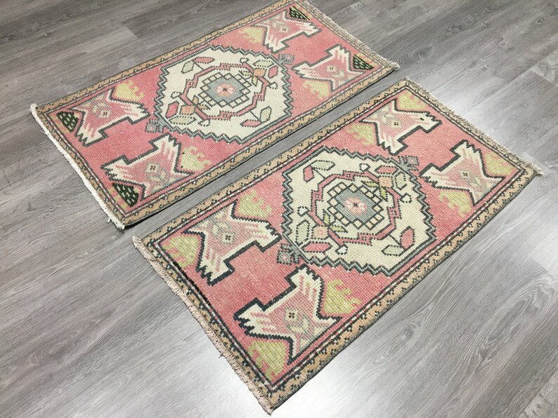 May include: Two pink and cream patterned runner rugs with geometric designs. The rugs have a fringed edge.