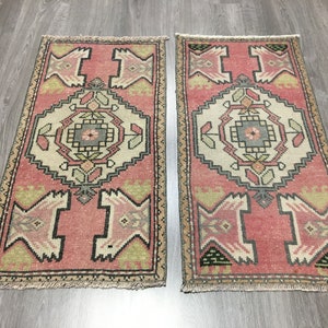May include: Two pink and beige patterned runner rugs with a geometric design. The rugs have a fringe border.