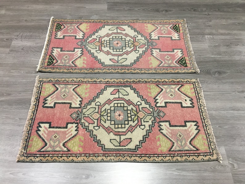 May include: Two pink and cream patterned rugs with intricate designs. The rugs have a fringed edge and are made of a soft, woven material.