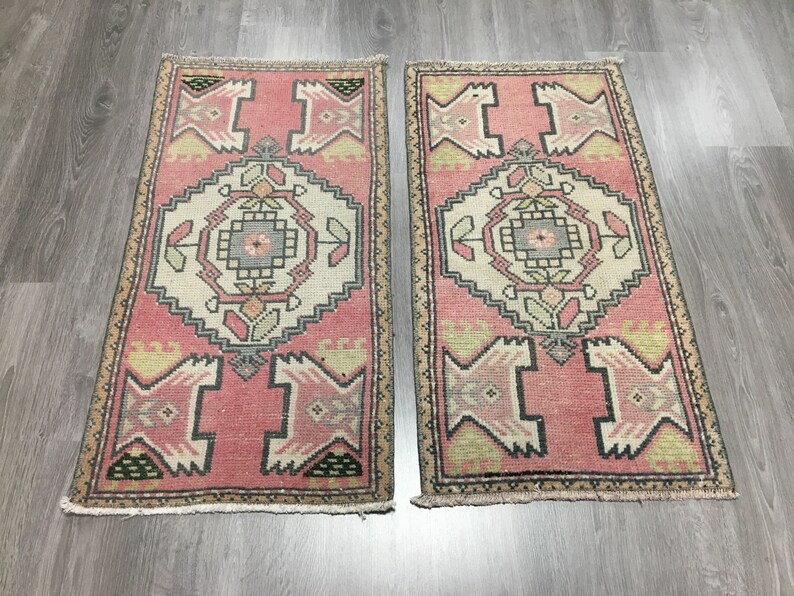 May include: Two pink and cream patterned runner rugs with a geometric design. The rugs have a fringe border.