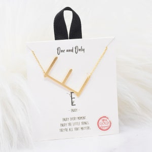May include: Gold initial E necklace on a white card with the text "One and Only" and "Enjoy every moment. Enjoy the little things. They're all that matters." The card also has a red circle with the text "18K Gold dipped".