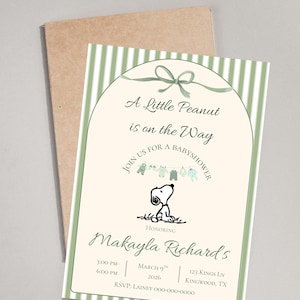 May include: Baby shower invitation featuring Snoopy, with text "A Little Peanut is on the Way." The invitation has a green and white striped border and includes event details. A brown envelope is behind the invitation.