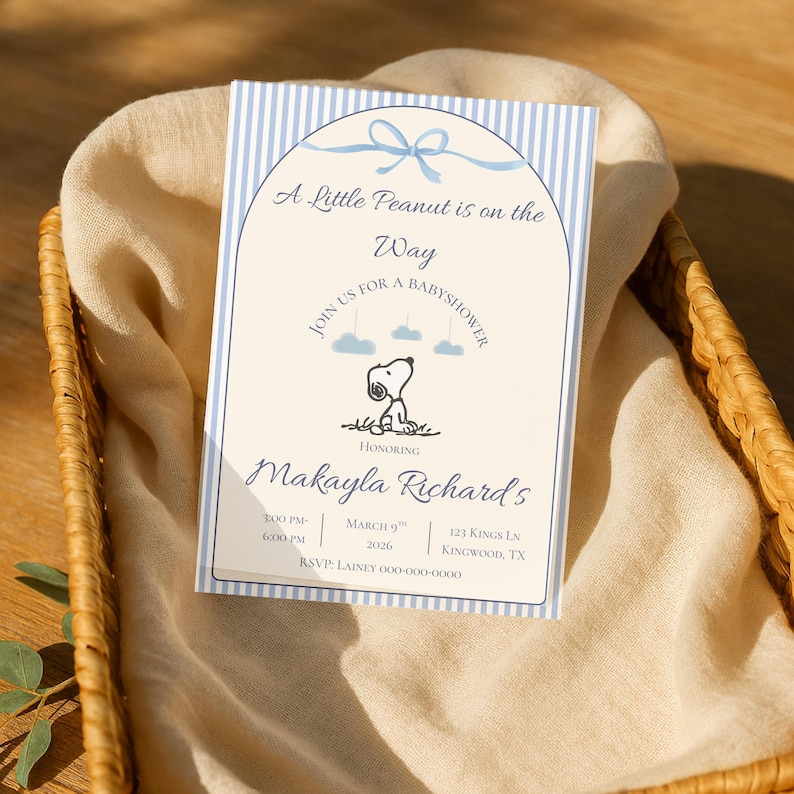 May include: Baby shower invitation with blue striped border and text "A Little Peanut is on the Way." Features a Snoopy graphic and event details. The invitation is on a beige background.