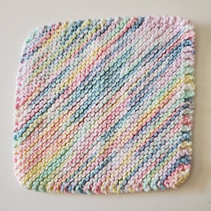 May include: A multi-colored knitted dishcloth with a diagonal pattern in shades of pink, blue, yellow, and green.