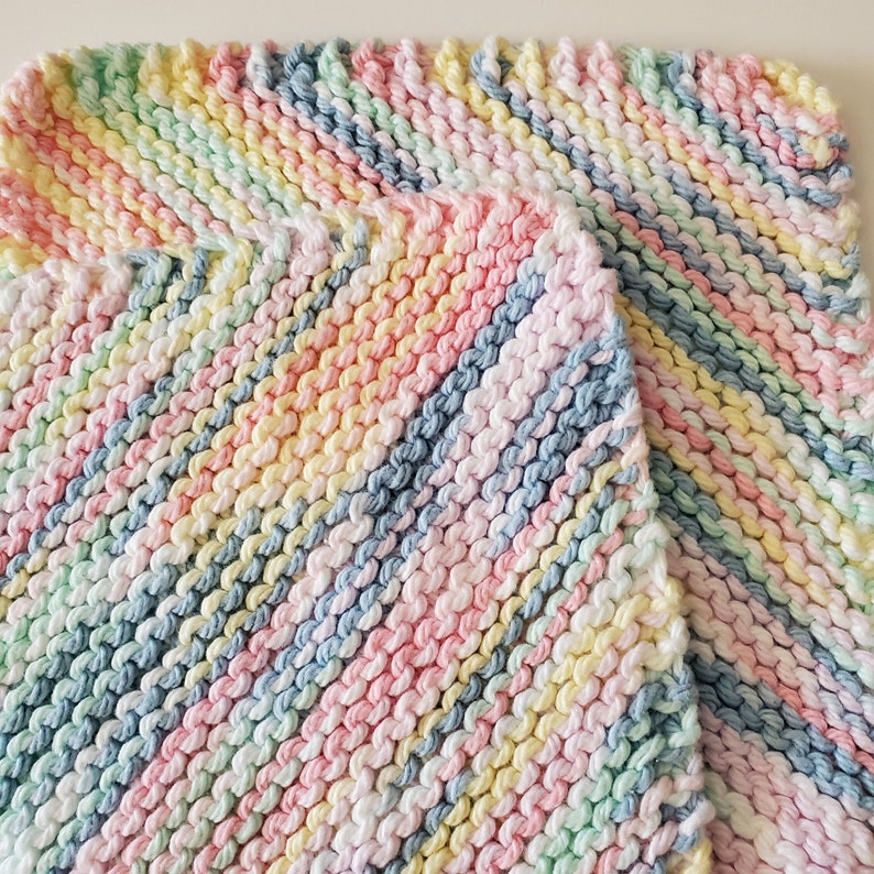 May include: A multi-colored knitted baby blanket with stripes of pink, blue, yellow, and green.