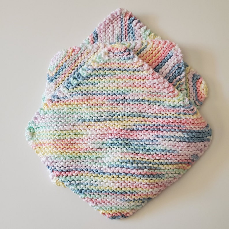 May include: Two pastel-colored knitted dishcloths with a striped pattern in shades of pink, blue, yellow, and white.