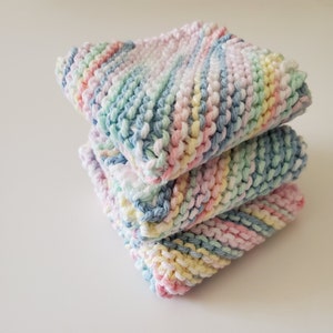 May include: A stack of three knitted dishcloths in pastel colors, including pink, blue, yellow, and green. The dishcloths are made with a textured stitch and have a soft, absorbent feel.