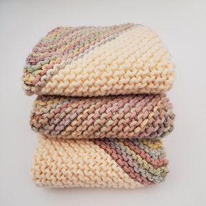 3 cloths knitted with 100% cotton yarn - 1 cloth is variegated with light yellow, blue, pink and a hint of light green yarn. 2 cloths cornered on 2 opposite corners with variegated and the middle is cream cotton yarn. Sizes 6, 7, 8, or 8.5-9 inches.