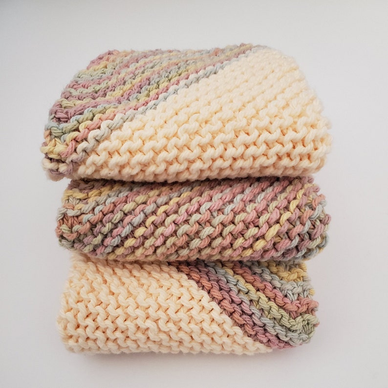 3 cloths knitted with 100% cotton yarn - 1 cloth is variegated with light yellow, blue, pink and a hint of light green yarn. 2 cloths cornered on 2 opposite corners with variegated and the middle is cream cotton yarn. Sizes 6, 7, 8, or 8.5-9 inches.