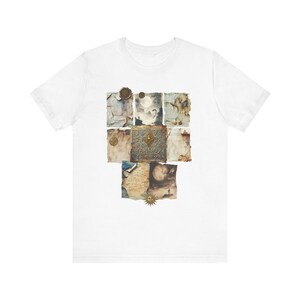 Könnte beinhalten: Ein weißes Kurzarm-T-Shirt mit einer zentralen grafischen Collage aus gealtertem Pergamentpapier, einem dunklen, verzierten Buchdeckel mit goldenem Emblem, Wachssiegeln und himmlischen Illustrationen, darunter ein Mond- und ein Sonnensymbol.