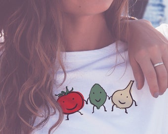 May include: White t-shirt with a graphic of a tomato, avocado, and onion with faces. The text "Urban Domestic Diva SHOP" is on the bottom right corner of the shirt.