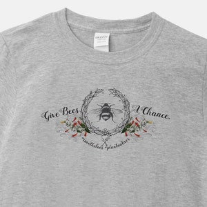 May include: Gray t-shirt with a graphic design of a bee in a wreath with the text "Give Bees A Chance. save the bees plant flowers"