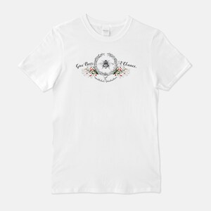 May include: White t-shirt with a graphic of a bee in a wreath of flowers and the text "Give Bees a Chance.  Pollinators of Happiness."