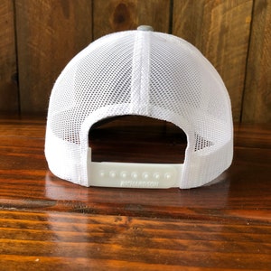 May include: A white and gray mesh baseball cap with a white adjustable strap that says "RICHARDSON" on it.