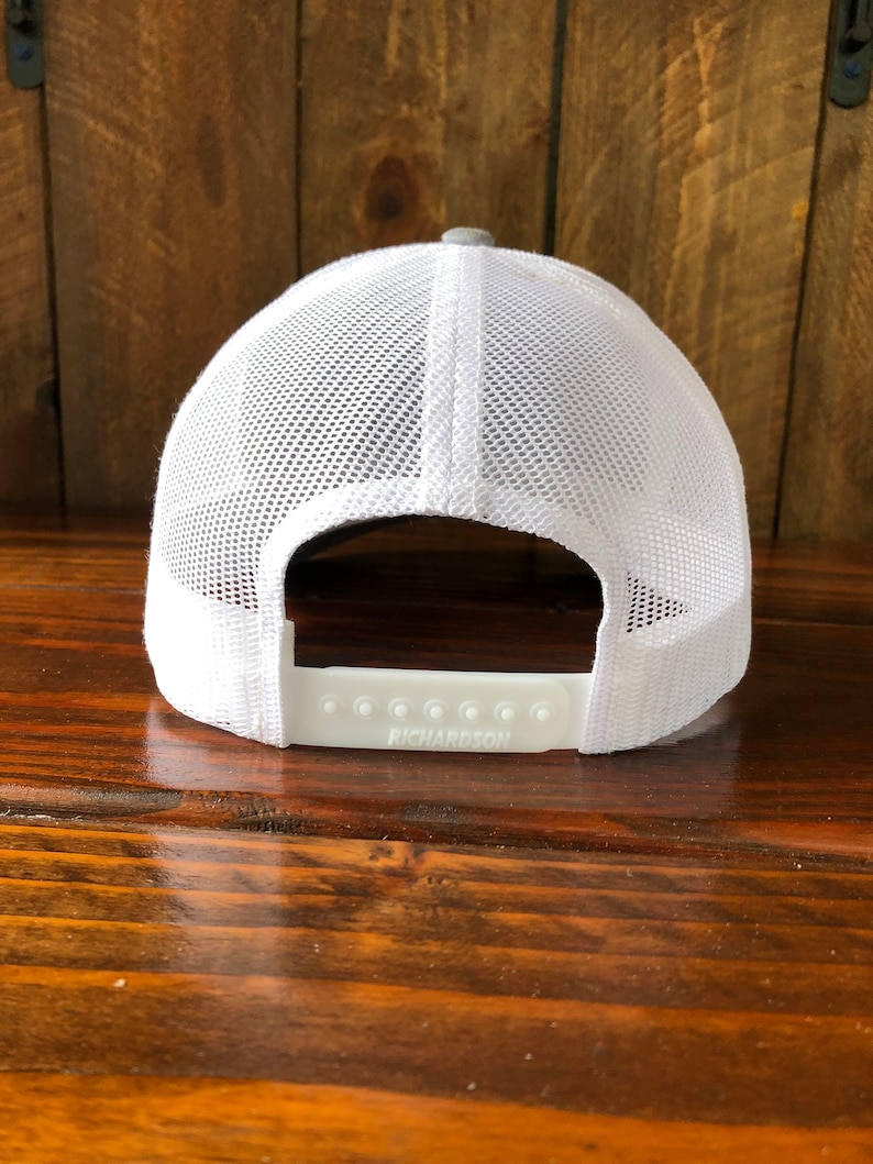 May include: A white and gray mesh baseball cap with a white adjustable strap that says "RICHARDSON" on it.