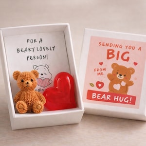 May include: A gift box with a knitted brown teddy bear and a red heart. The box has the text "FOR A BEARY LOVELY PERSON!" inside. The lid has a bear graphic and the words "SENDING YOU A BIG BEAR HUG!"