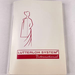 May include: A white rectangular folder featuring a red line drawing of a person wearing a garment on the upper left side. Below the drawing, a red rectangular box contains the text LUTTERLOH SYSTEM in white, with the word International below it.