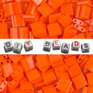 May include: A large pile of bright orange plastic letter beads. The beads spell out "DIY BEADS".