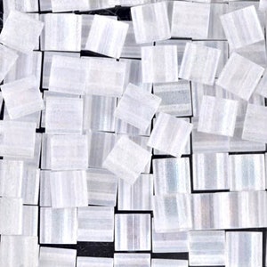 May include: A collection of small, white, iridescent square tiles. The tiles have a subtle striped pattern and are perfect for crafting projects.