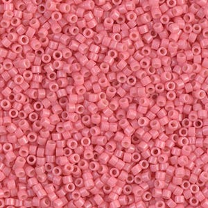 May include: Close-up of a pile of small, cylindrical, light pink beads. The beads are uniform in size and shape, with a hole running through the center of each. The beads are scattered, creating a textured surface. Ideal for jewelry making and crafts.