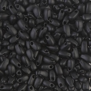 May include: A close-up of a pile of black seed beads with a matte finish. The beads are small and oval-shaped with a hole at one end.