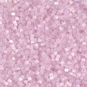 May include: A close-up view of a large quantity of small, light pink, square-shaped beads. The beads have a slightly iridescent finish.