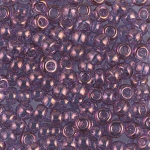 May include: A close-up of a large quantity of small, round, iridescent purple glass beads. The beads have a slightly faceted surface and are perfect for jewelry making.