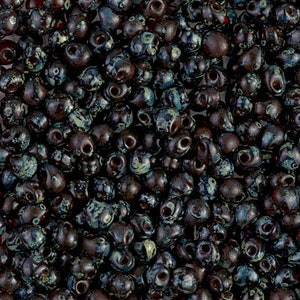 May include: A close-up image of a large quantity of dark brown and teal glass beads. The beads are small and have a speckled, irregular surface.