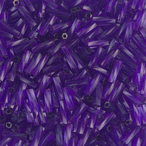 May include: A close-up of a pile of purple glass beads. The beads are long and thin, with a slightly iridescent finish.