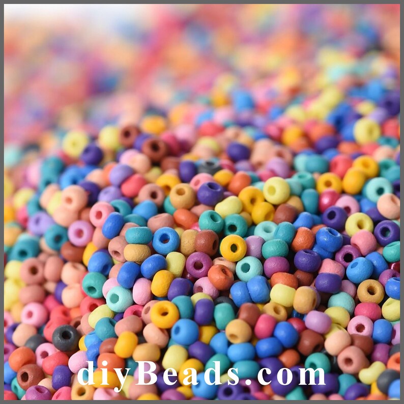 Peut inclure: Une grande collection de petites perles rondes au fini mat dans un assortiment vibrant de couleurs incluant bleu, jaune, rose, violet, orange et marron. Le texte "diybeads.com" est imprim&eacute; en blanc au bas de l'image.
