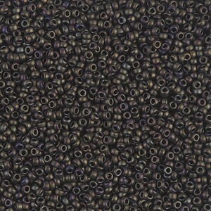 May include: A close-up view of a large quantity of small, round, dark gray seed beads. The beads have a subtle iridescent sheen.