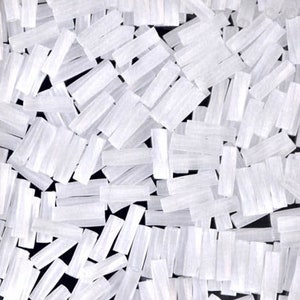 May include: A close-up image of a pile of white selenite crystal sticks. The sticks are various lengths and widths, and they are all translucent.
