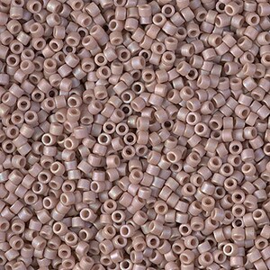 May include: A close-up view of a large quantity of small, round, iridescent beads. The beads are a light, dusty rose color with a subtle shimmer.