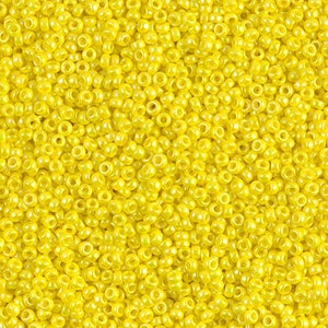May include: A close-up view of a large quantity of small, round, yellow seed beads. The beads have a slight sheen and are perfect for crafting.