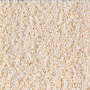 May include: A close-up image of a large quantity of small, white, round seed beads. The beads have a slight iridescent sheen.