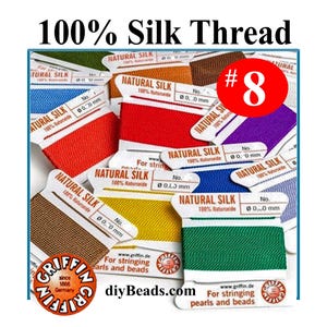 May include: A collection of Griffin brand 100% natural silk thread spools in various colors including red, blue, yellow, green, brown, and purple. Each spool is labeled with the text Natural Silk and includes an attached needle for stringing.