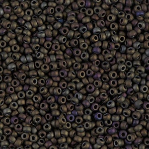 Puede incluir: Una imagen de primer plano de una gran cantidad de pequeñas cuentas redondas de color marrón oscuro con un sutil brillo iridiscente.