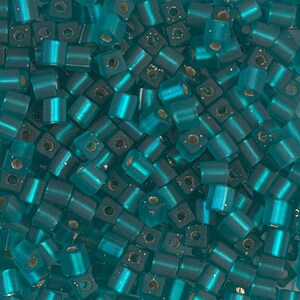 May include: A large pile of teal blue square glass beads. The beads have a slightly iridescent finish.